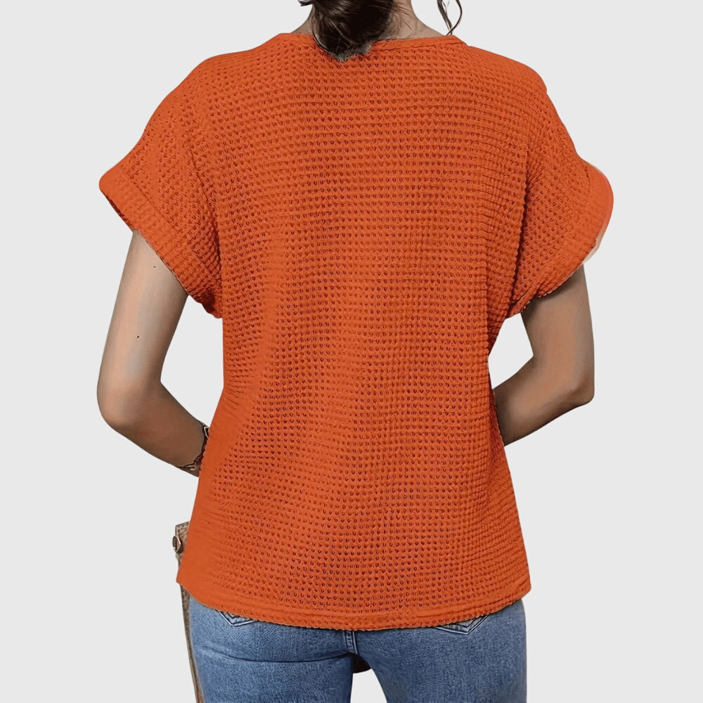 Isabel y Miguel Madrid Perla™ Ibiza style elegant blouse with flowing fabric and intricate detailing, displayed on a hanger.