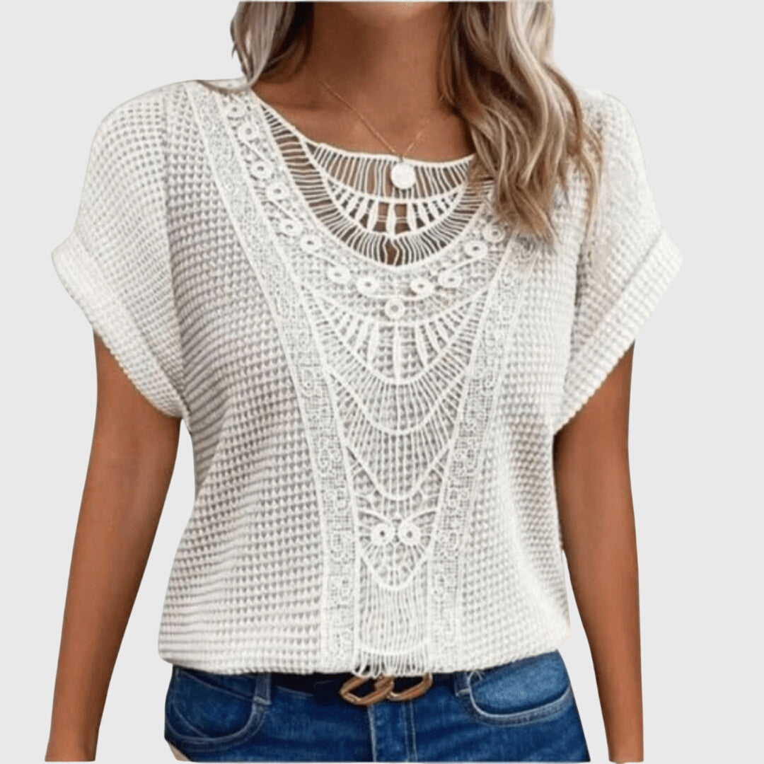 Isabel y Miguel Madrid Perla™ Ibiza-style elegant blouse with flowy fabric and intricate embroidery, displayed on a hanger.
