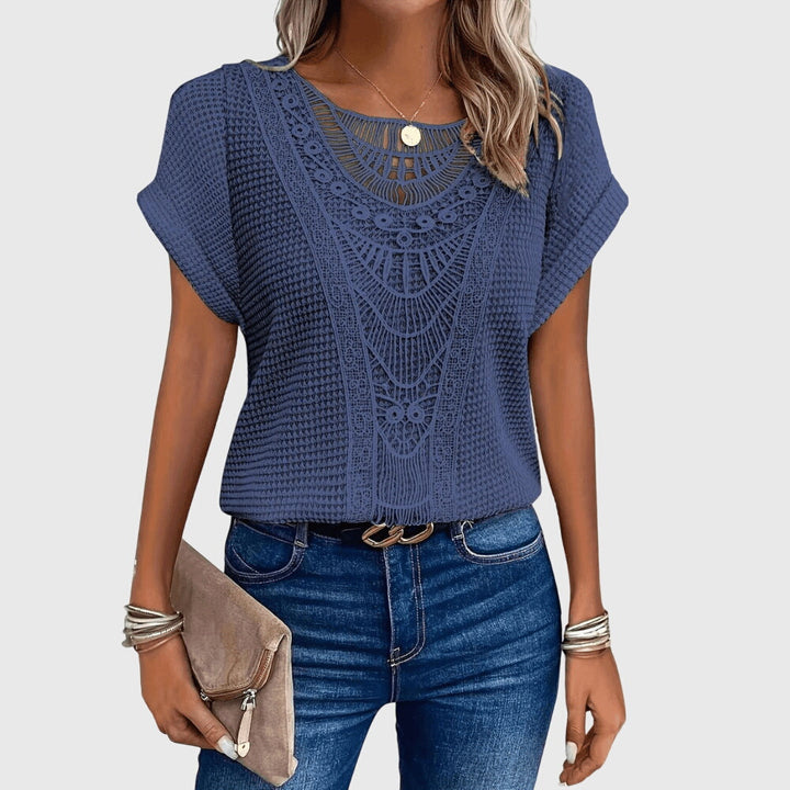 Isabel y Miguel Madrid Perla™ Ibiza-style elegant blouse with flowing fabric and intricate embroidery, displayed on a hanger.