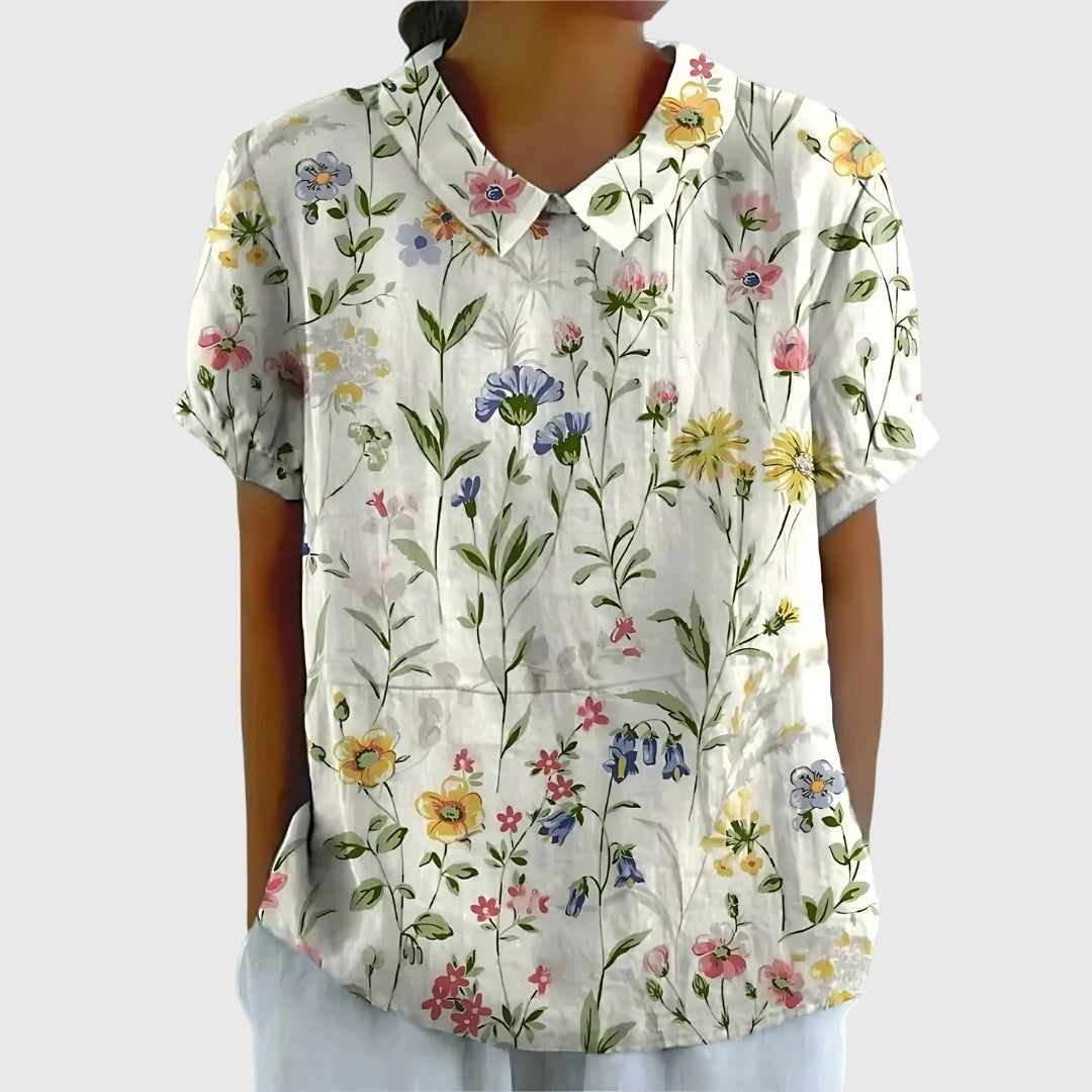 Isabel y Miguel Madrid Jenna floral blouse with colorful flower print, lightweight fabric, and long sleeves, displayed on a hanger.