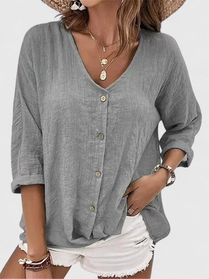 Isabel y Miguel Madrid Kylie elegant blouse in white with ruffled neckline and long sleeves, displayed on a hanger.