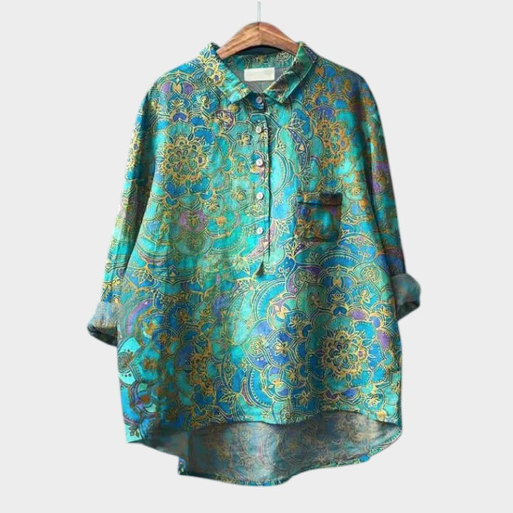 Light blue women's blouse by Isabel y Miguel Madrid, featuring a relaxed fit and stylish neckline, displayed on a hanger.