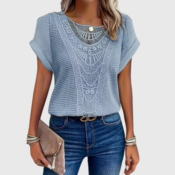 Isabel y Miguel Madrid Perla™ Ibiza style elegant blouse with flowing fabric and intricate embroidery, displayed on a hanger.